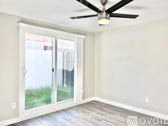 A room with a ceiling fan and sliding glass doors.