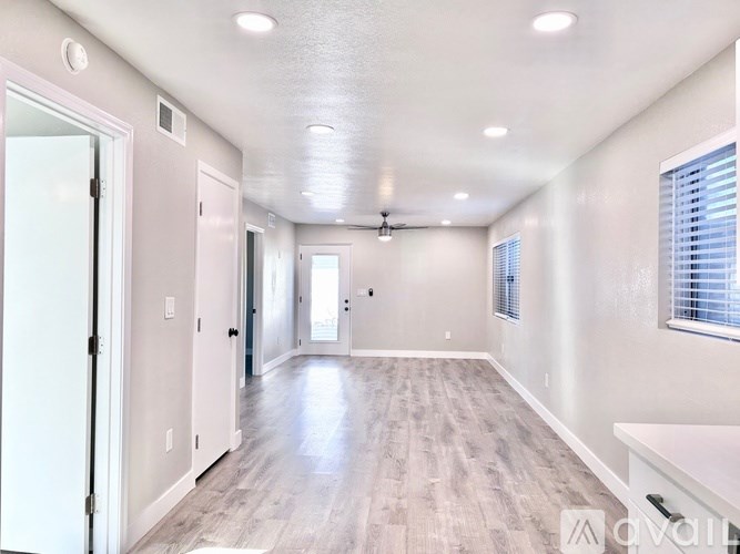 A spacious room with a white ceiling and wooden flooring.