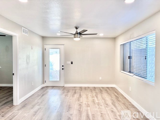 A spacious room with a ceiling fan and a door leading to a balcony.