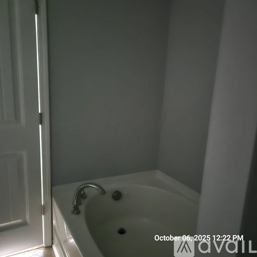 A white bathtub with a silver faucet is in a bathroom with a white door.