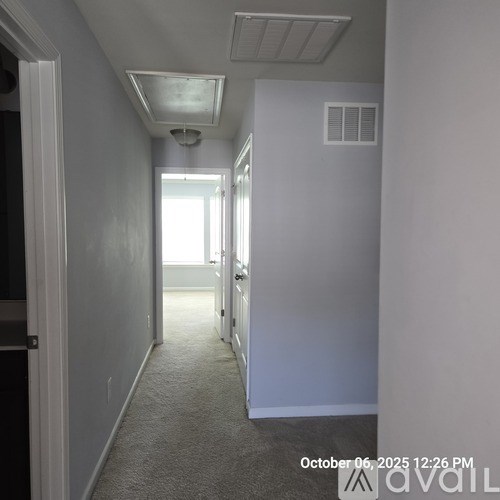 A long, narrow hallway with a carpeted floor and white walls.