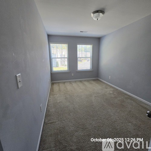 A room with a window and a carpeted floor.