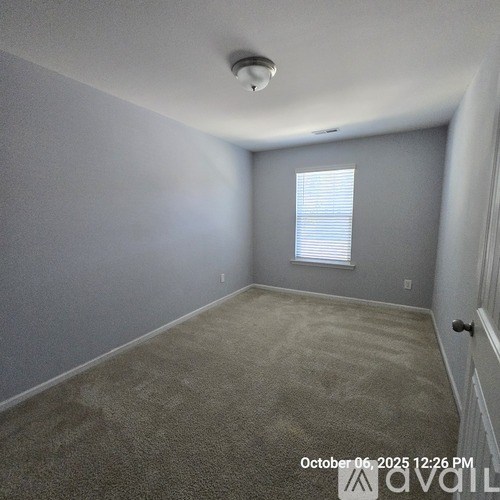 A room with a smoke detector on the ceiling and a window with blinds.