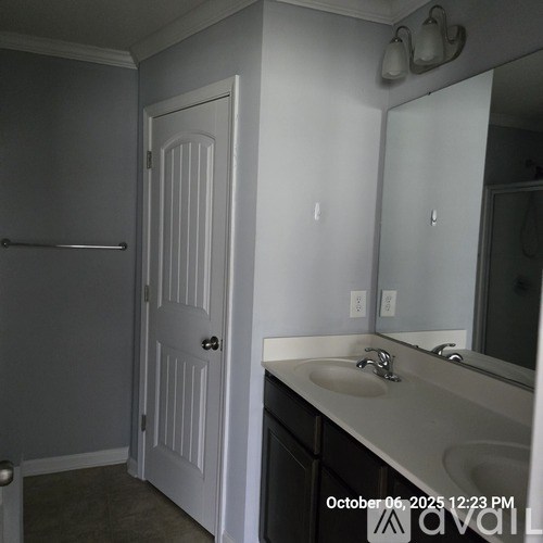 A bathroom with a white door, sink, and mirror.