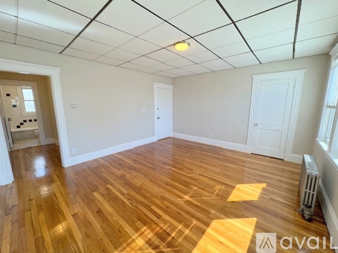 A room with wooden flooring and white walls is available for rent.