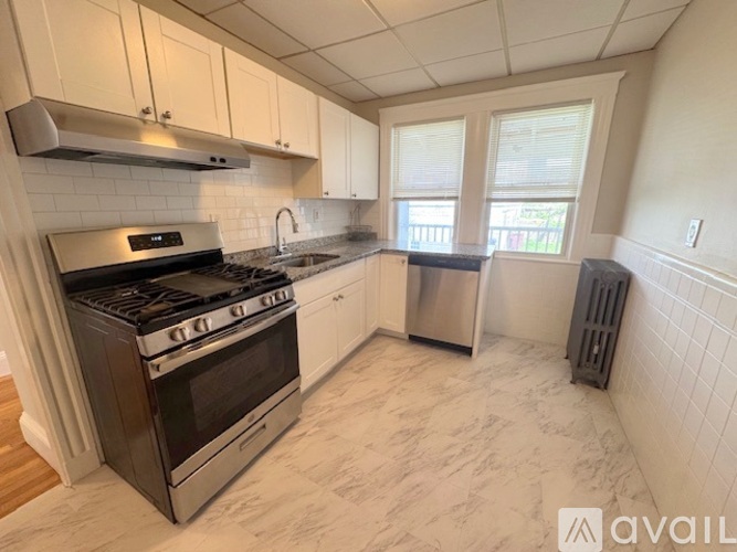 A kitchen with a stove, sink, and cabinets.