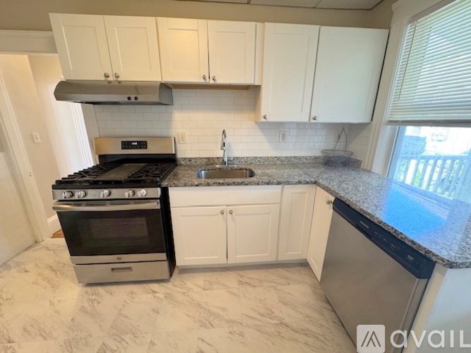 A kitchen with a stove, sink, and cabinets.