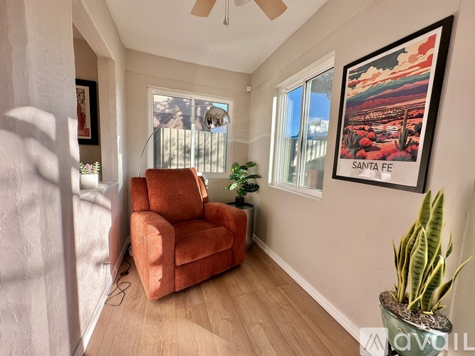 A living room with a red chair and a Santa Fe poster on the wall.
