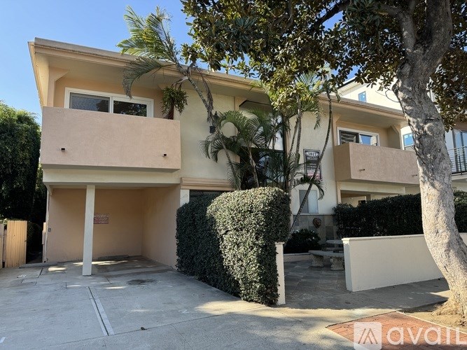 A two-story house with a balcony and a tree in front.