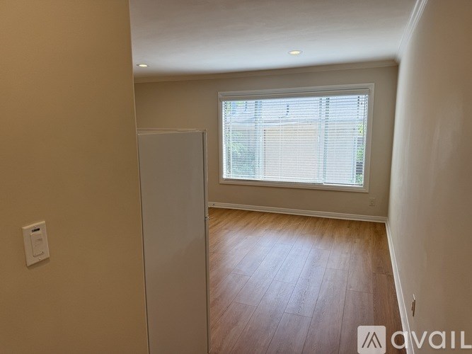 A room with a wooden floor and a window with blinds.