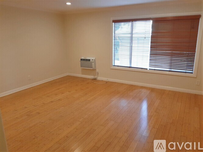 A room with wooden flooring and a window with blinds.