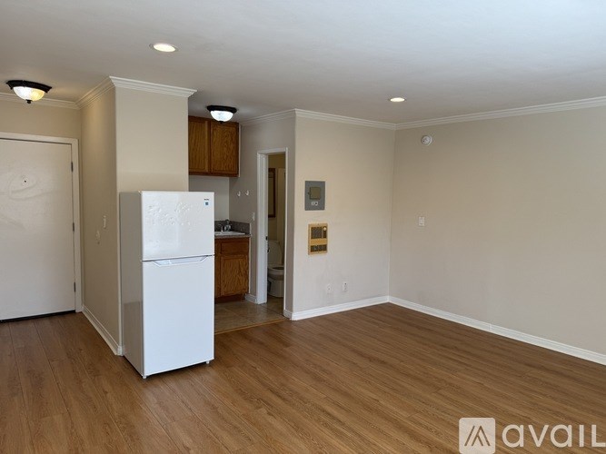 A white refrigerator is in a kitchen with wood cabinets.