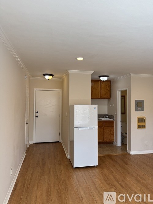 A kitchen with a white fridge and wooden floors.