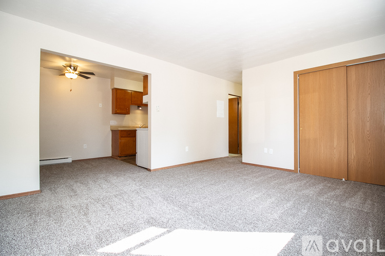 A spacious room with a ceiling fan and a door leading to another room.