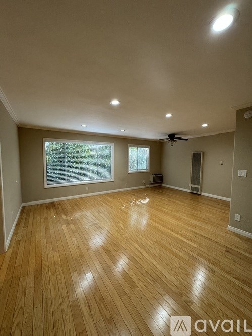 A spacious room with wooden flooring and a ceiling fan.