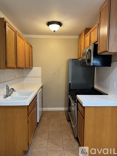 A kitchen with wooden cabinets and a black microwave above the stove.