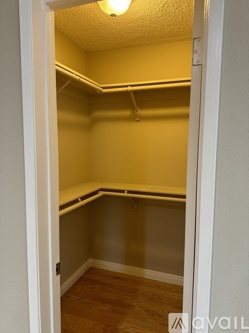 A small, empty room with a wooden floor and white walls.