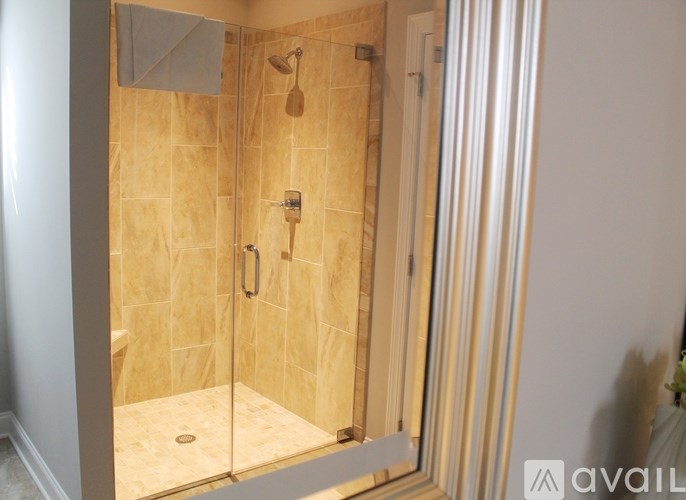 A bathroom with a walk-in shower and a glass door.
