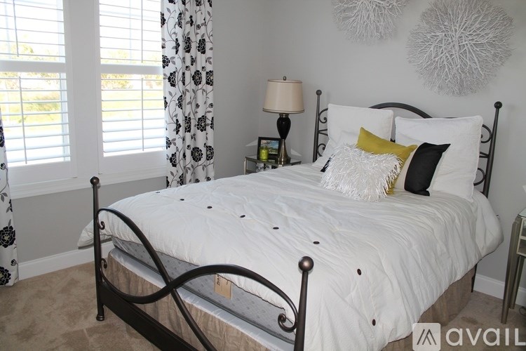 A bed with a white comforter and a black metal frame.