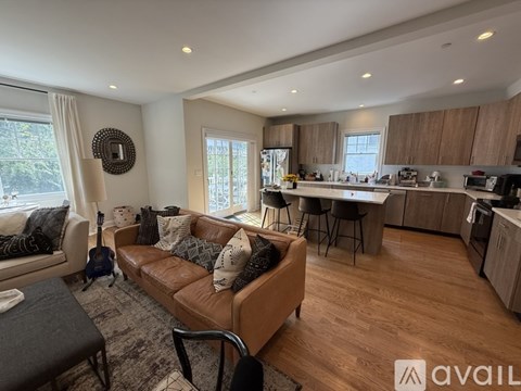 A living room with a brown leather couch and a wooden floor.