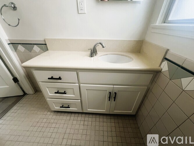 A bathroom with a sink, a cabinet, and a tiled floor.