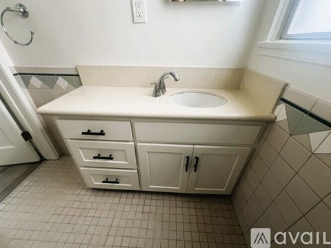 A bathroom with a sink, a cabinet, and a tiled floor.