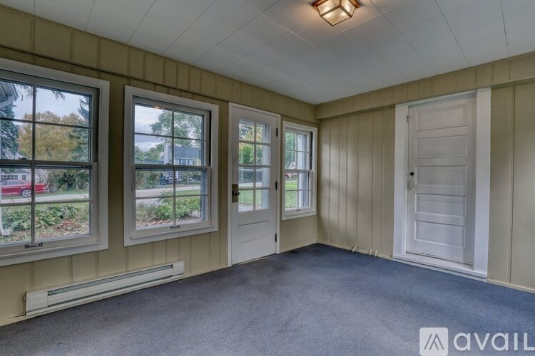 A room with a large window and a lamp on the ceiling.