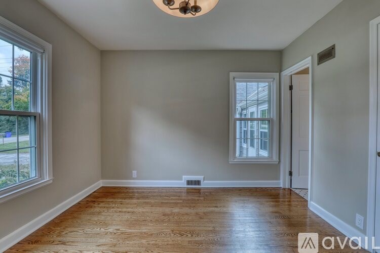 A room with wooden flooring and a window on the left side.