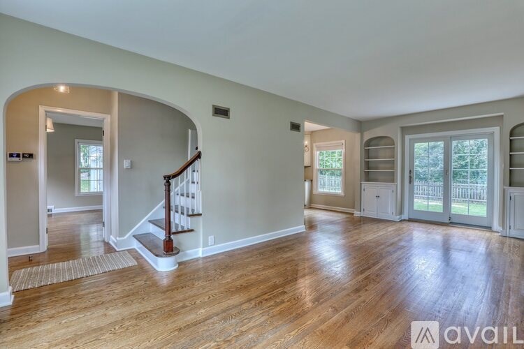 A spacious living room with hardwood floors and a staircase leading to the upper level.