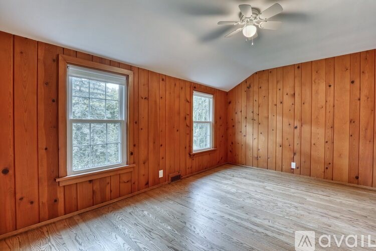 A room with wooden walls and a ceiling fan.