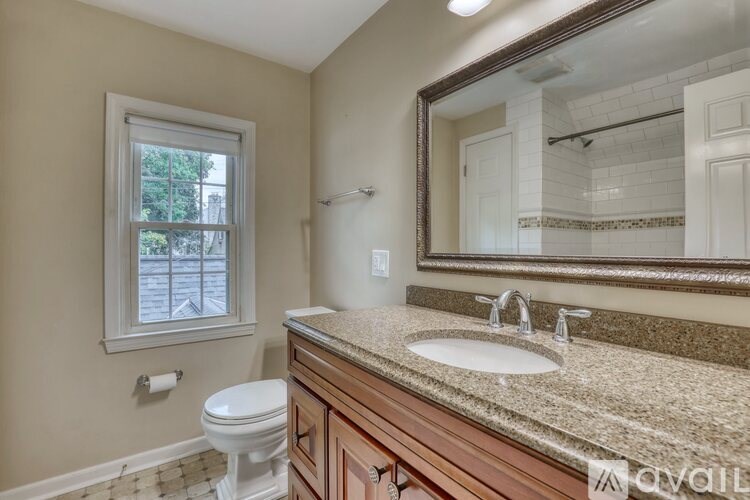 A bathroom with a toilet, sink, and mirror.