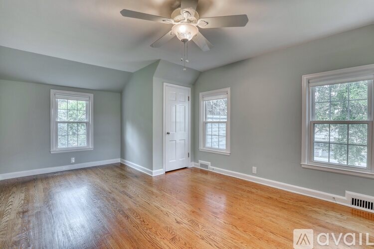 A room with a ceiling fan and hardwood floors.