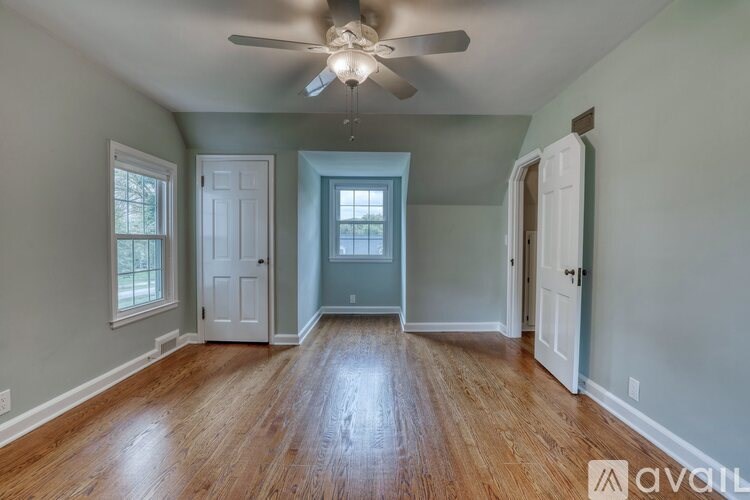 A room with a ceiling fan and wooden floors.