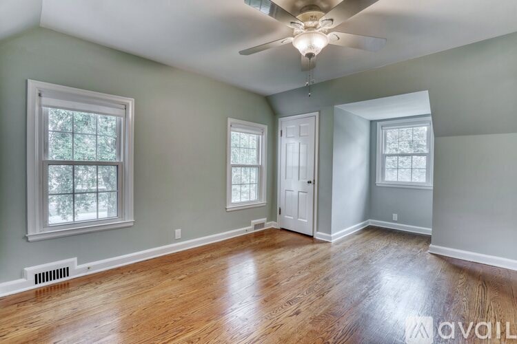 A room with a ceiling fan and wood flooring.