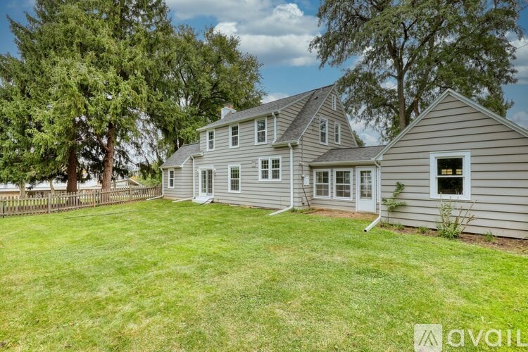A house with a large lawn and trees in the background.