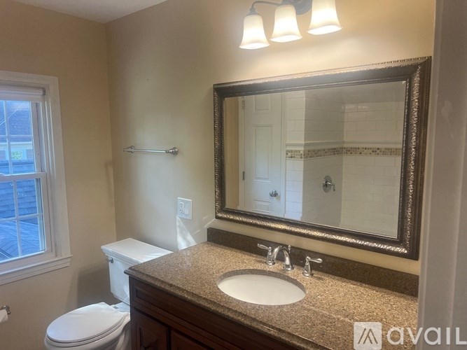 A bathroom with a toilet, sink, and mirror.