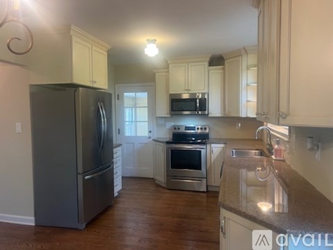 A kitchen with a black refrigerator and stainless steel appliances.