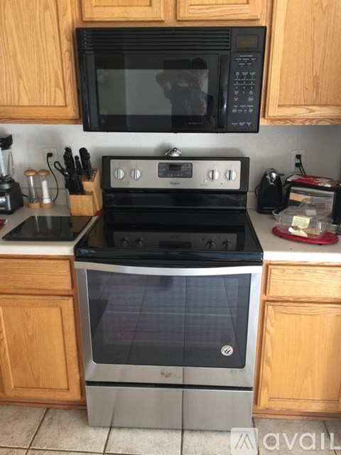 A black microwave is mounted above a stove in a kitchen.