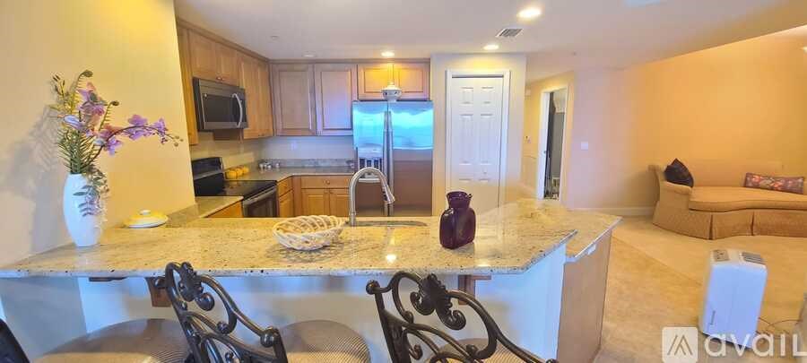 A kitchen with granite countertops and a refrigerator in the background.