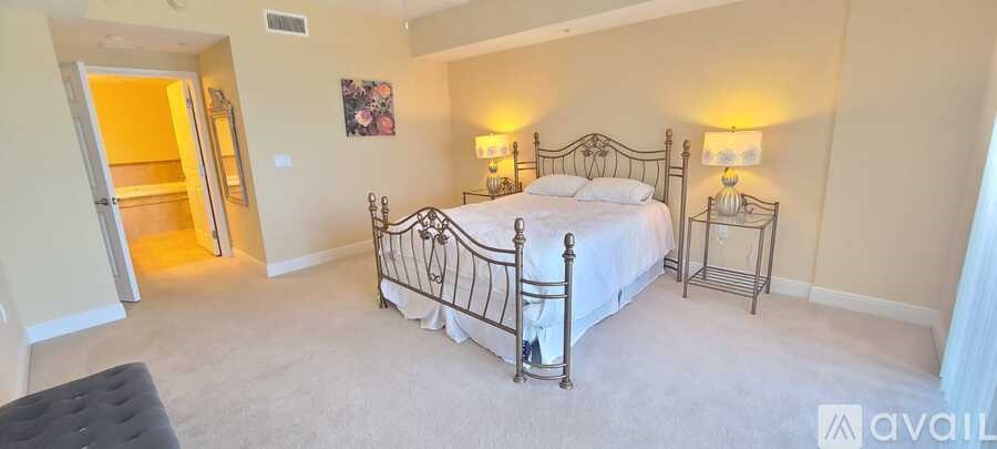 A bedroom with a large bed and two lamps.