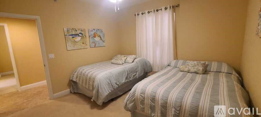 Two twin beds in a room with two paintings on the wall.