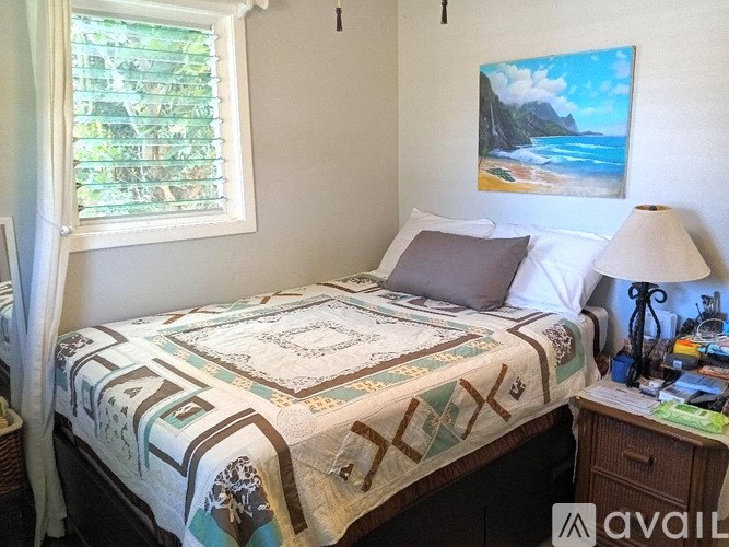 A bedroom with a bed, nightstand, and a painting of a beach scene on the wall.