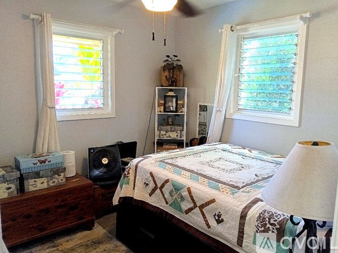 A bedroom with a bed, a ceiling fan, and a window with blinds.