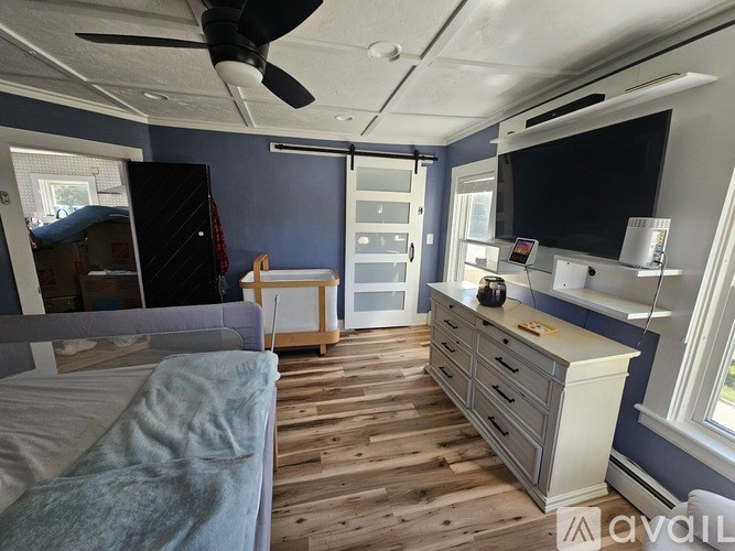 A bedroom with a bed, dresser, and ceiling fan.