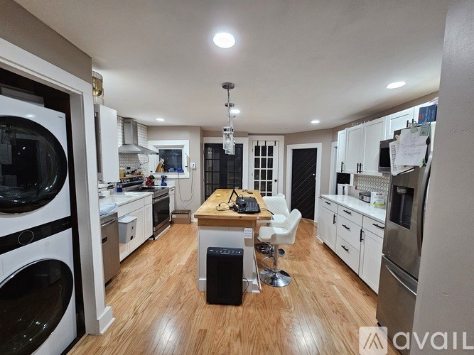 A modern kitchen with wooden floors and white appliances.