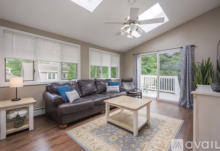 A living room with a brown leather couch, a wooden coffee table, and a ceiling fan.
