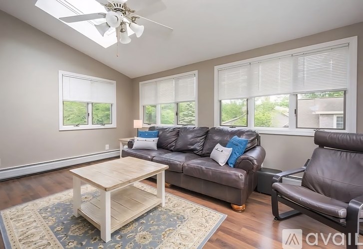 A living room with a brown couch, a wooden coffee table, and a ceiling fan.
