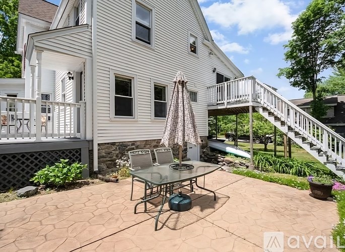 A patio with a table and chairs is in front of a house.