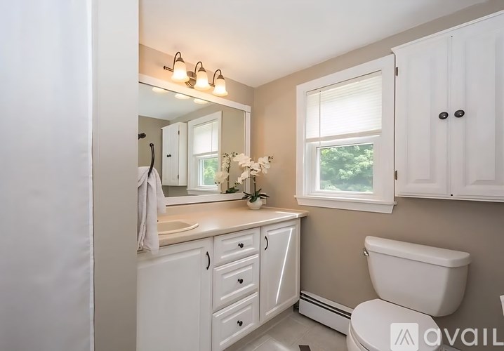 A white bathroom with a towel hanging on the door.