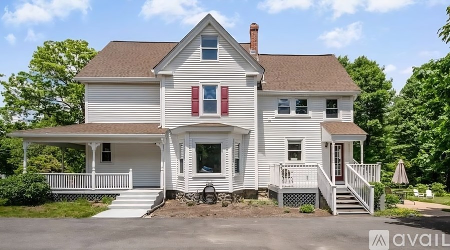 A white house with a brown roof and a red door.